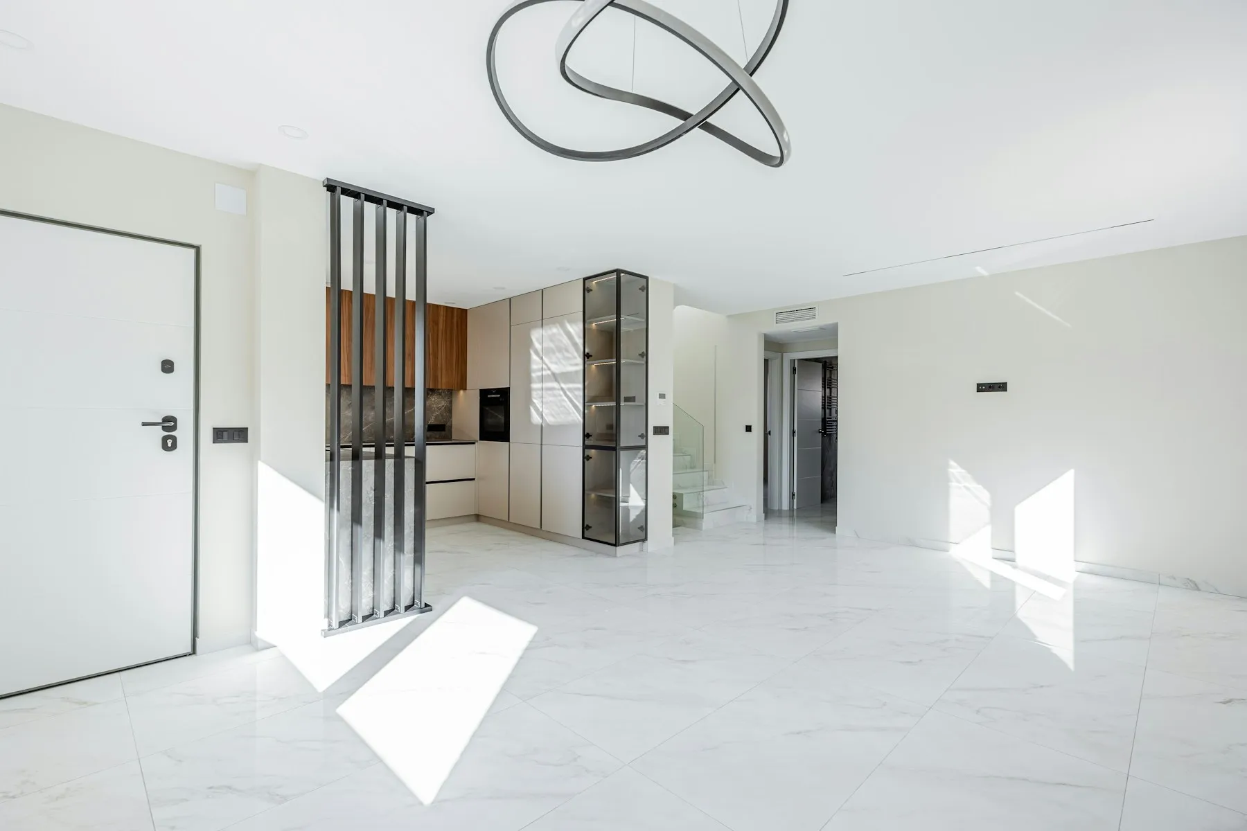 Salón-cocina contemporáneo con isla, celosía metálica y arranque de escalera
