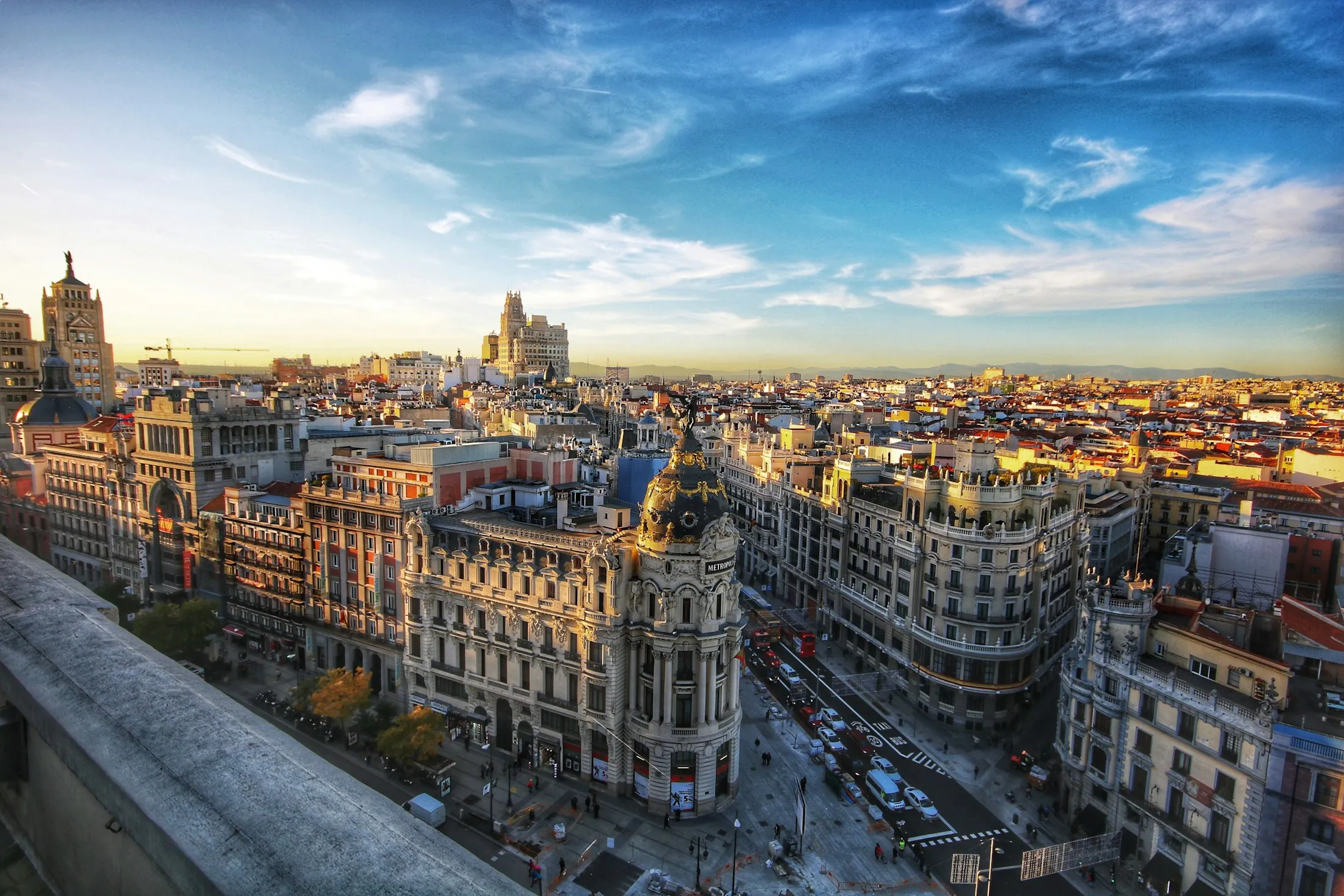 Fachadas señoriales de Madrid al atardecer, con el edificio Metrópolis al fondo