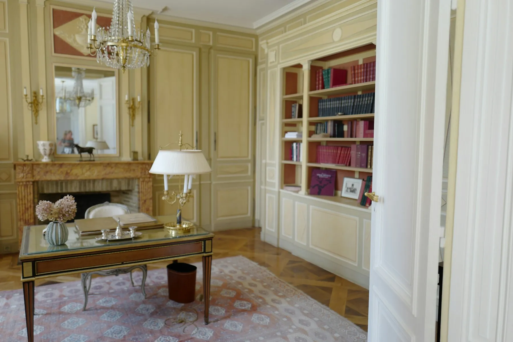 Salón-biblioteca clásico con boiserie, chimenea de mármol y parqué Versailles